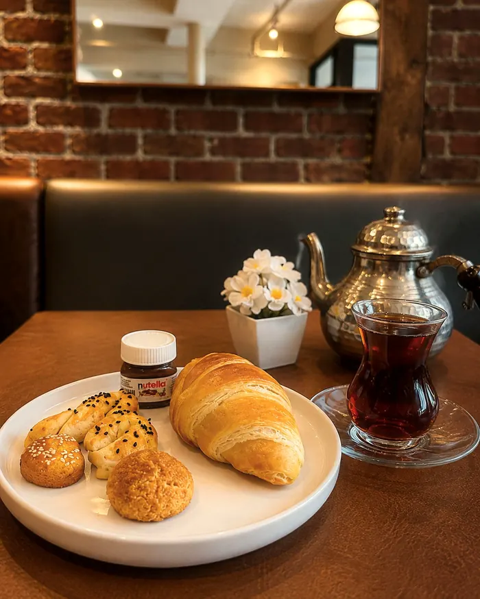 Croissant et petits pains, thé turc en verre tulipe et théière en métal